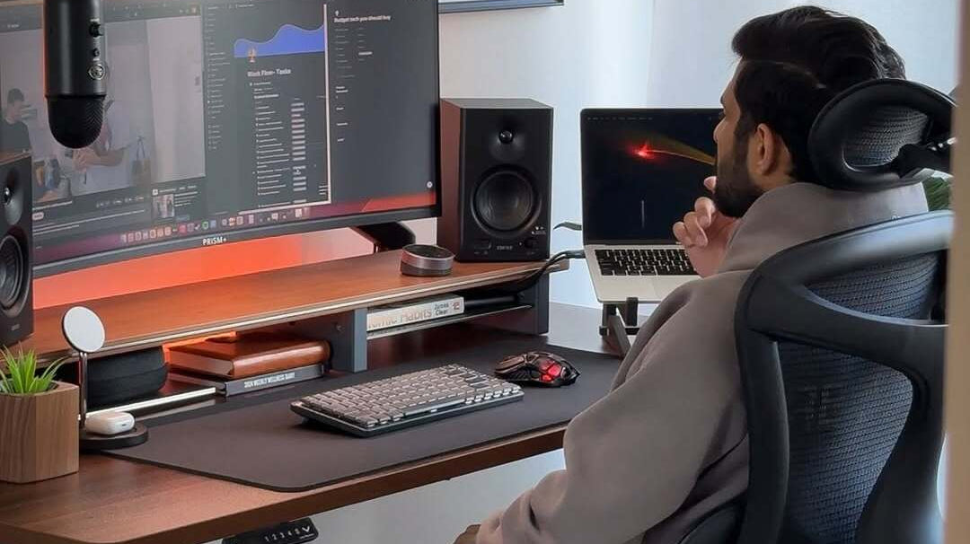 A man sitting on an ergonomic chair while working at his desk, illustrating the best office chairs for long hours of sitting with comfort and proper back support.