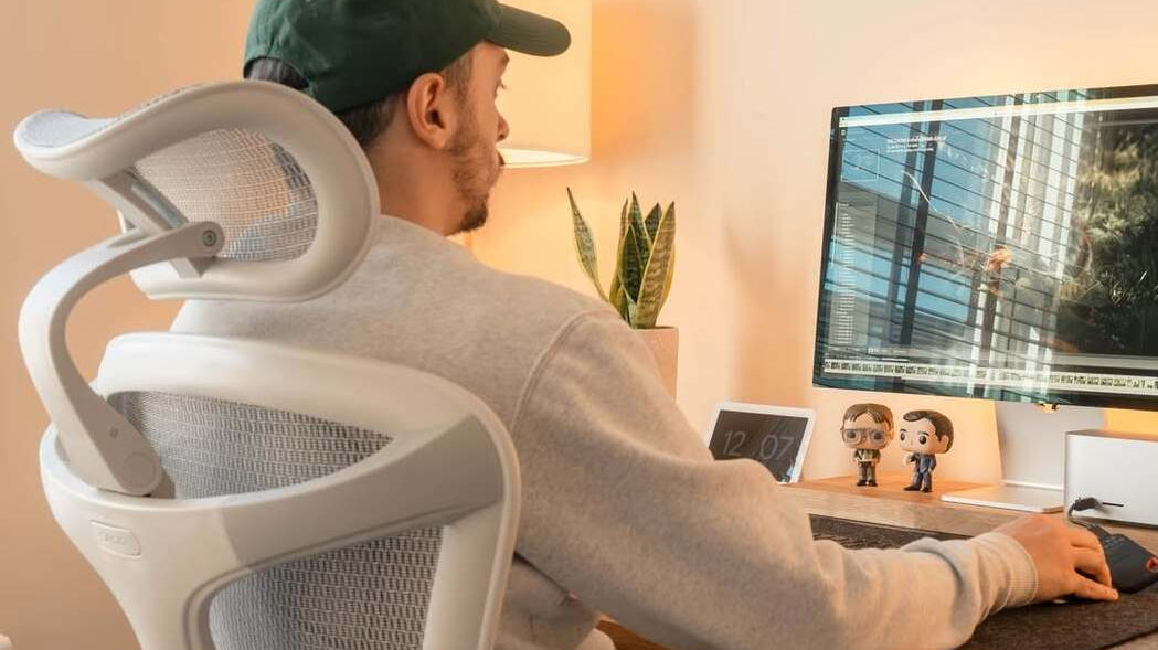 A man sitting on a computer chair, illustrating what to look for in a computer chair such as ergonomic design, lumbar support, and adjustable features for comfort and posture.