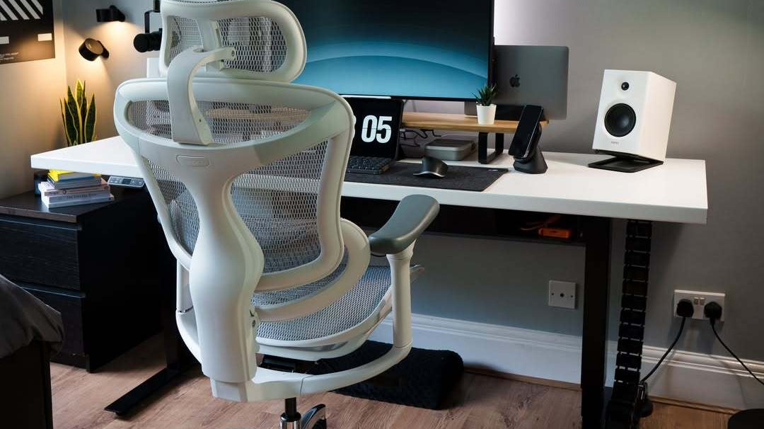 White ergonomic chair facing an office desk with a computer, illustrating how ergonomic setups can enhance work productivity through comfort and proper posture support