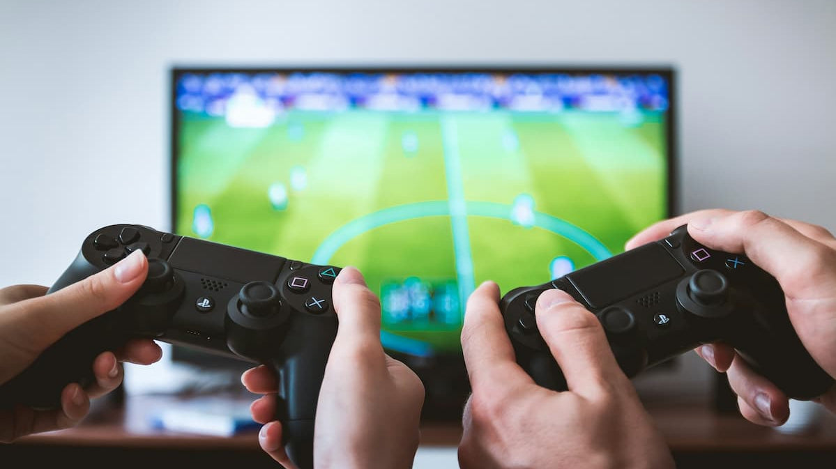 Couple enjoying a gaming setup for couples, playing a soccer video game with dual controllers on a large screen.