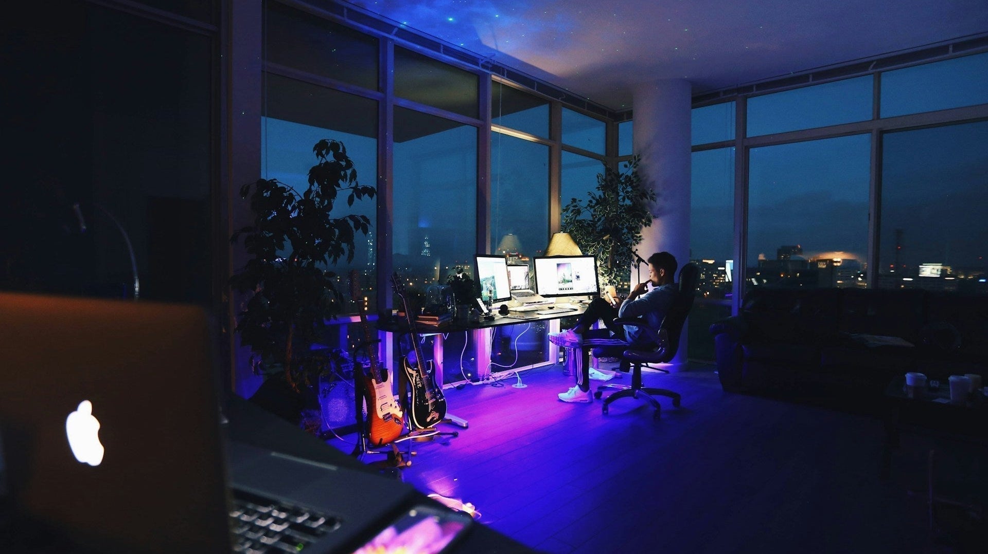 Home office lighting with multiple screens, desk lamp, and night city view. Image by Roberto Nickson via www.unsplash.com