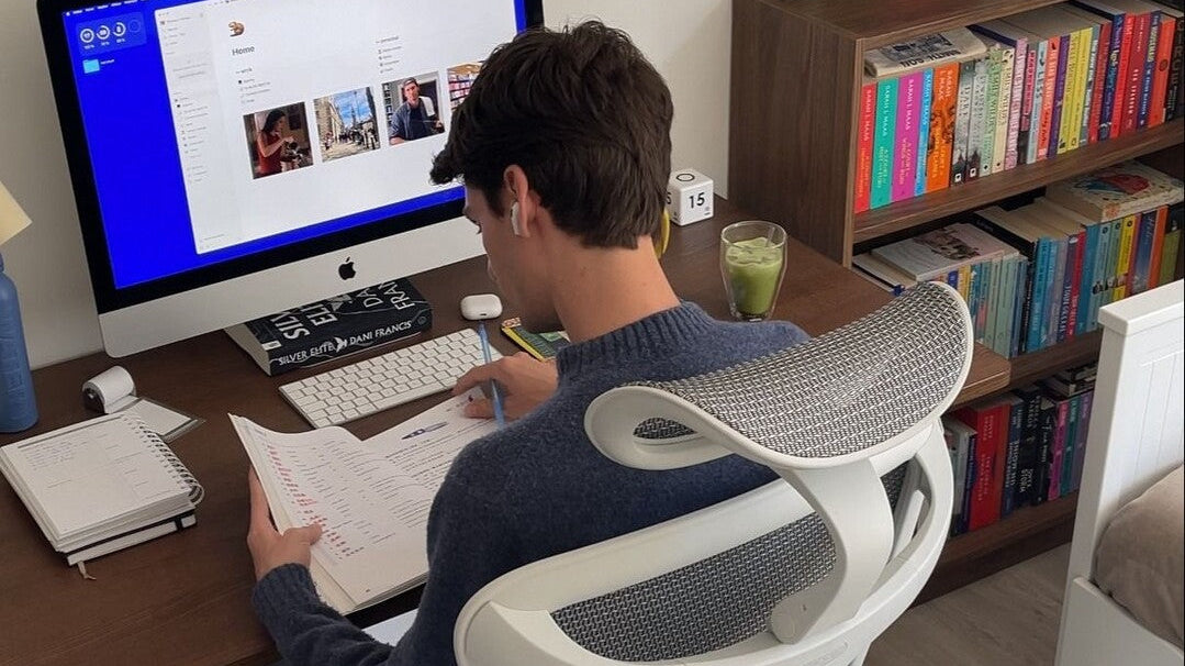A man studying on how to increase work productivity, sitting on an ergonomic chair by Sihoo.