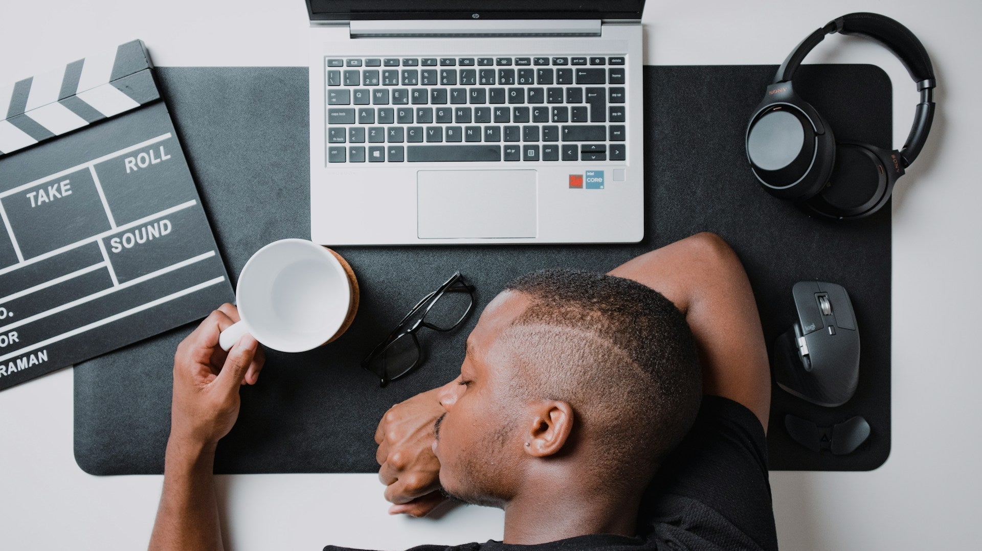 Man asleep at desk with laptop, coffee, and headphones, reflecting exhaustion and the question of how long does a burnout last in daily life. Image by Nubelson Fernandes via www.unsplash.com