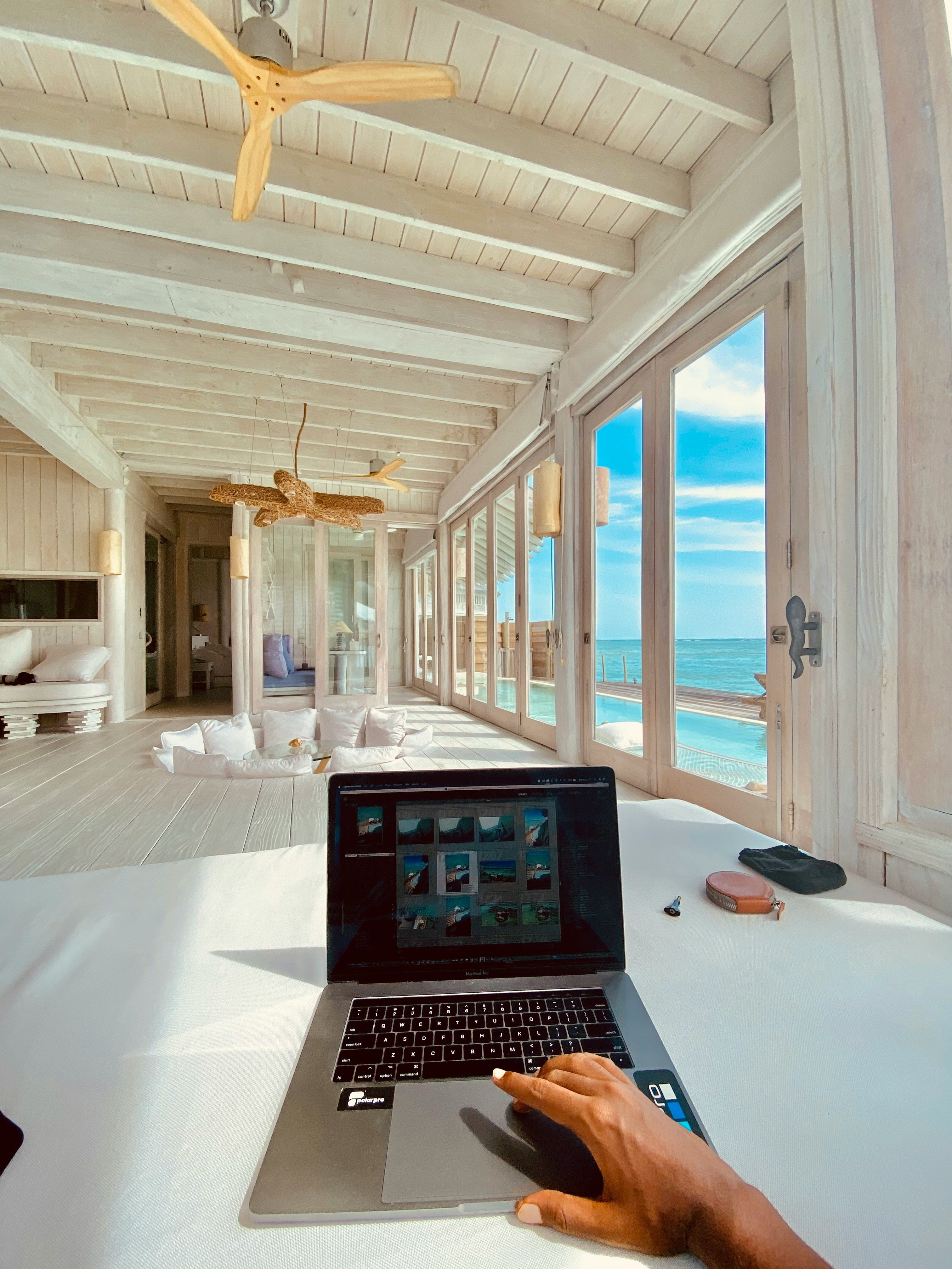 A laptop on a wooden desk in a bright coastal-inspired home office, showcasing natural light, and minimalist home office decorating ideas.