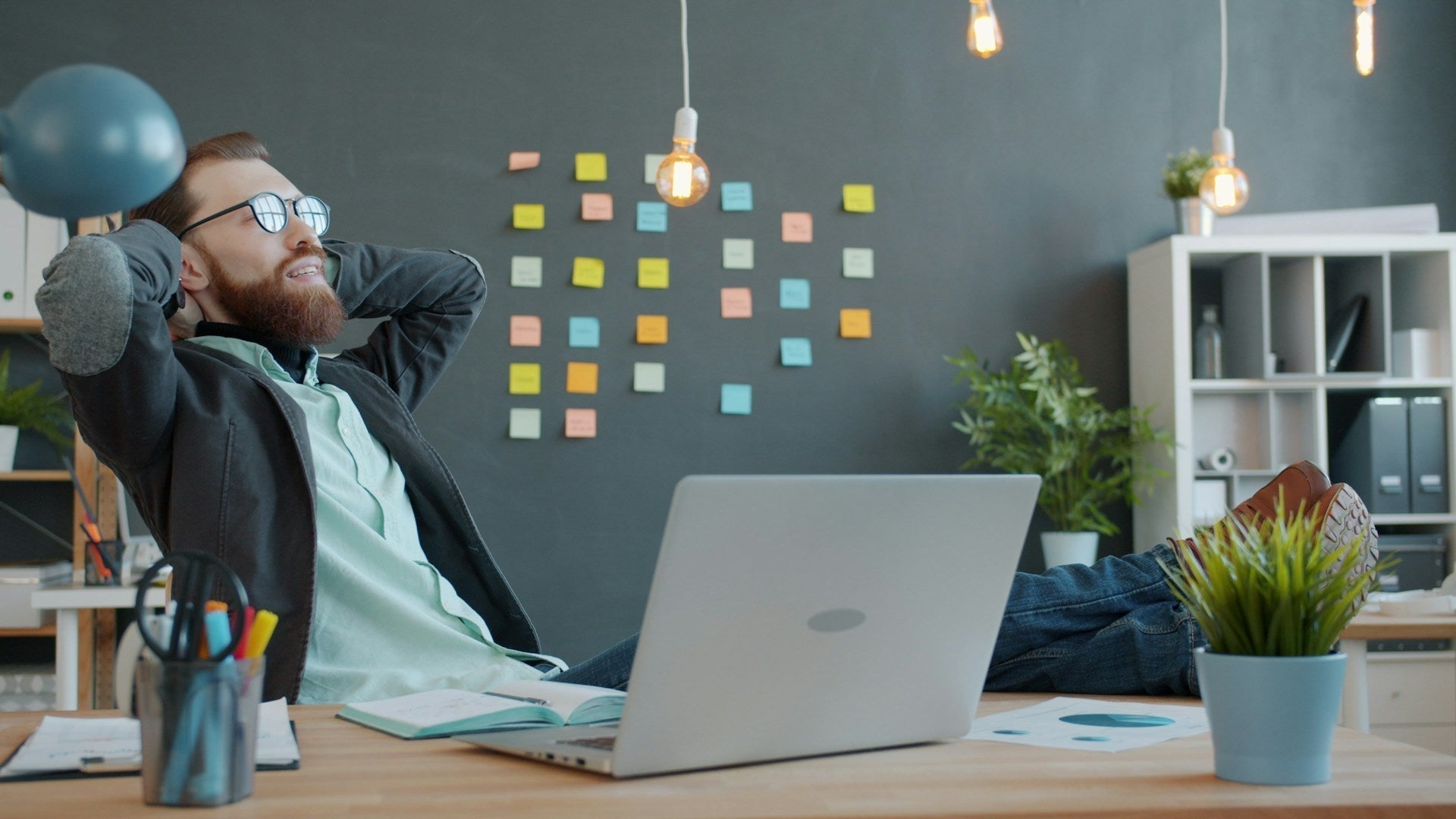 Man reclining with feet on desk in office, matching theme of 12 simple posture tips to ease lower back pain.