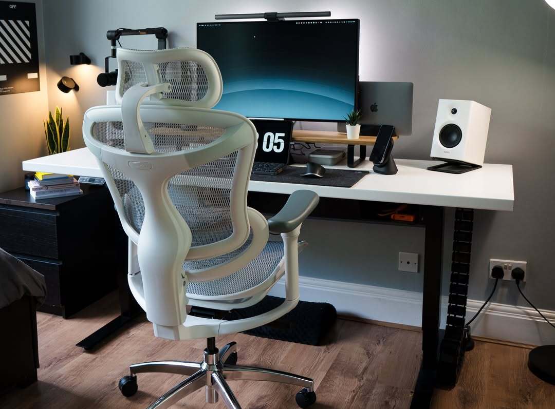 White ergonomic chair facing an office desk with a computer, illustrating how ergonomic setups can enhance work productivity through comfort and proper posture support