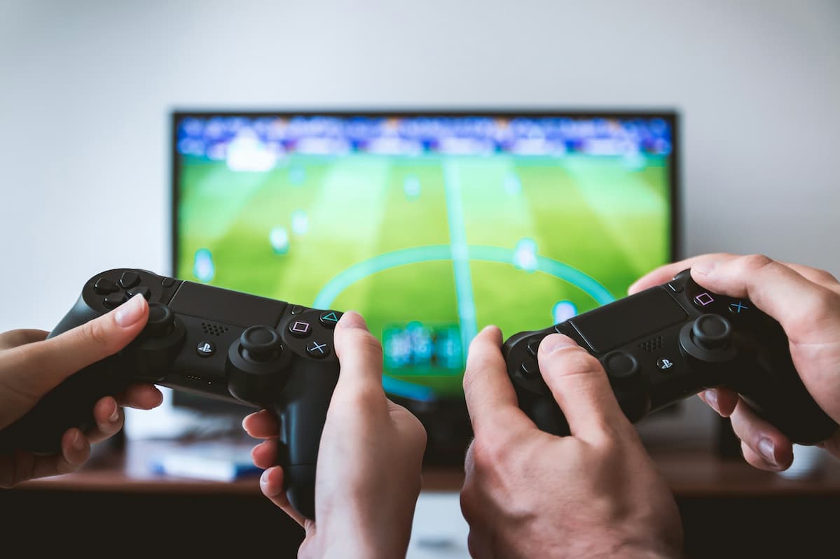 Couple enjoying a gaming setup for couples, playing a soccer video game with dual controllers on a large screen.