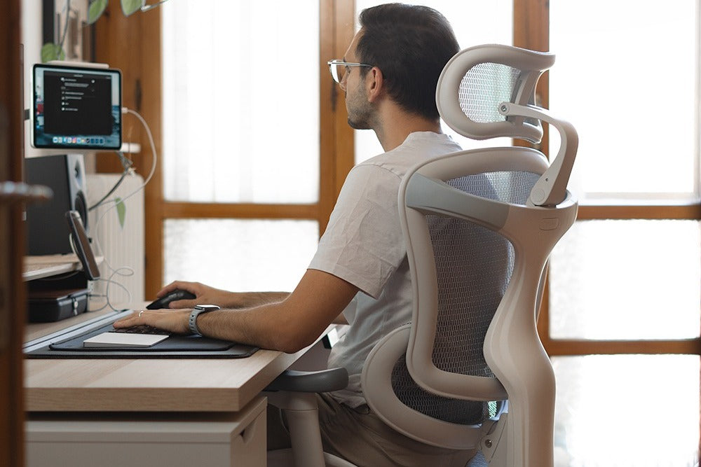 Man working at a desk with ergonomic chair and computer, related to tracking home office expenses.