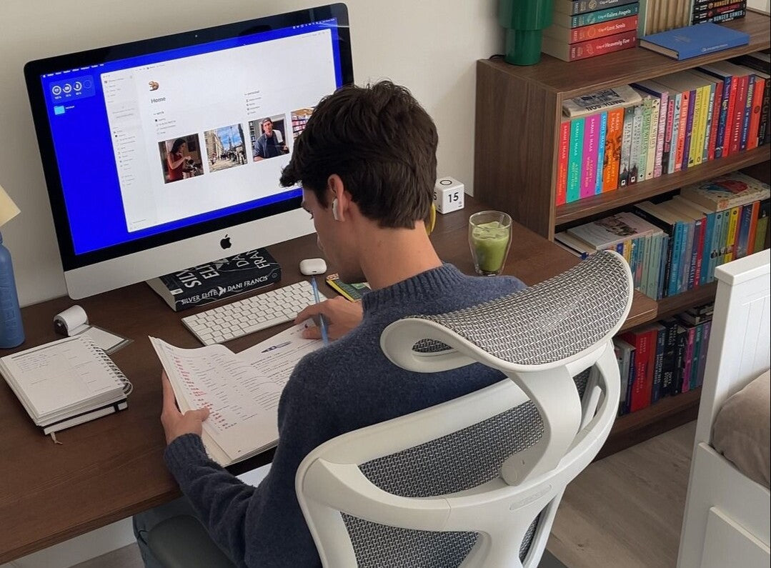 A man studying on how to increase work productivity, sitting on an ergonomic chair by Sihoo.