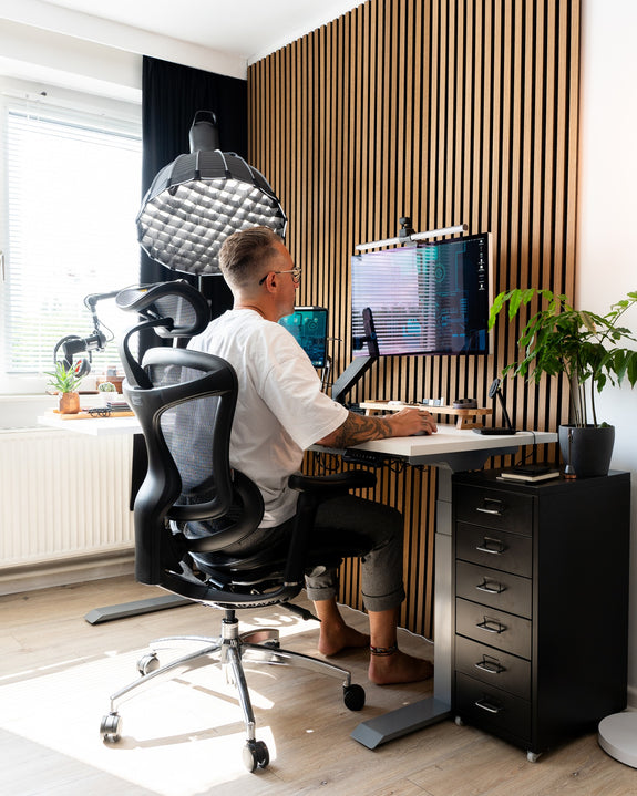 Man working in a work-from-home setup while seated on an ergonomic chair.