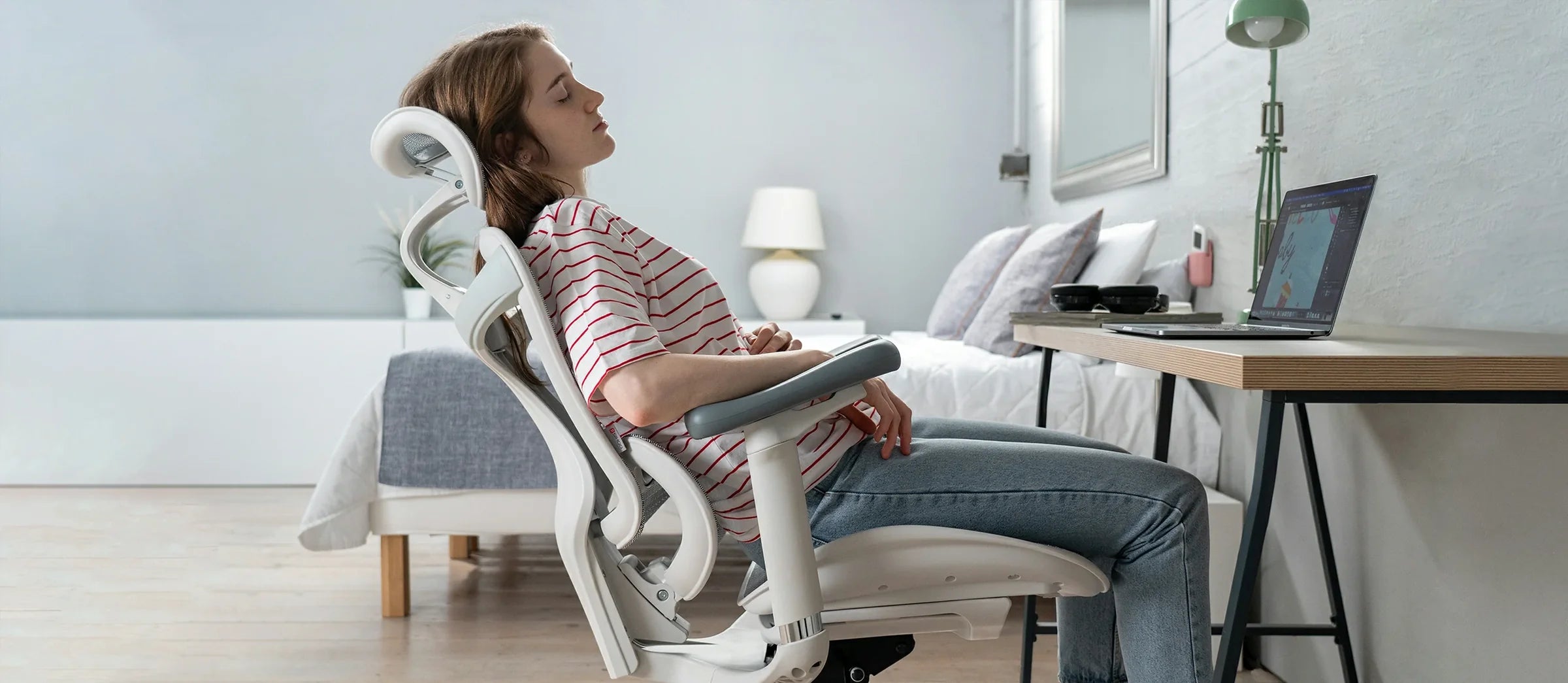 Woman relaxing on white Sihoo ergonomic chair in Australia in a home office setup with laptop and work desk.