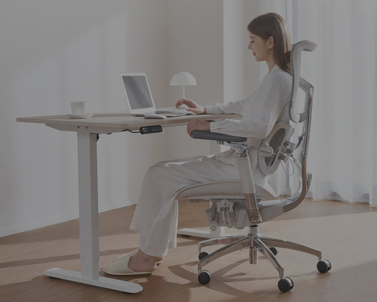 Person working on a laptop while sitting on a white ergonomic chair in a home office setup.